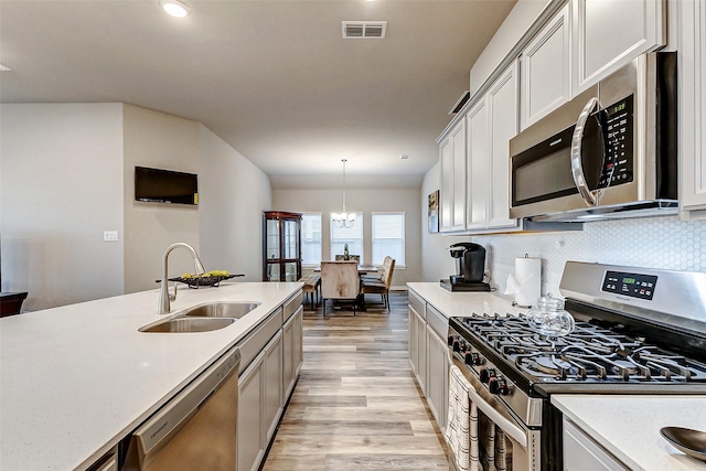 5110 Morrison Dr, Manvel, TX 77578 - kitchen featuring stainless steel appliances, a sink, light wood-style floors, decorative backsplash, and hanging light fixtures