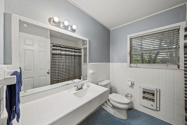 2310 Pecos St, La Marque, TX 77568 - bathroom featuring tile walls, heating unit, toilet, a sink, and tile patterned flooring