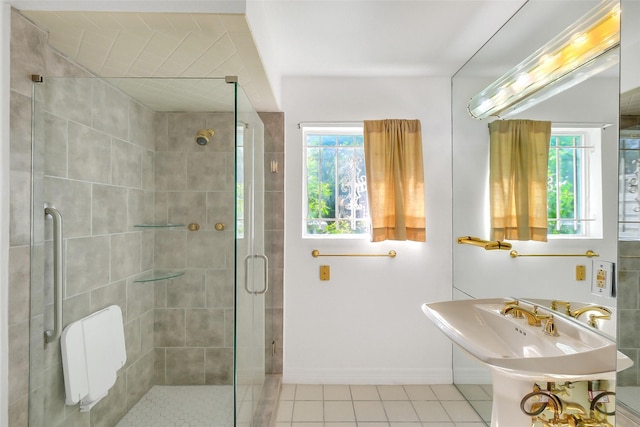 bathroom with plenty of natural light, a stall shower, tile patterned floors, and baseboards