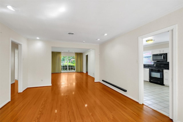 empty room with a baseboard radiator, light wood finished floors, baseboards, and recessed lighting