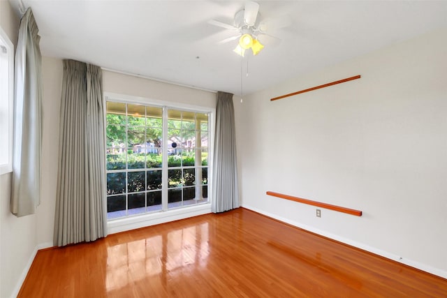 spare room with wood finished floors, ceiling fan, and baseboards