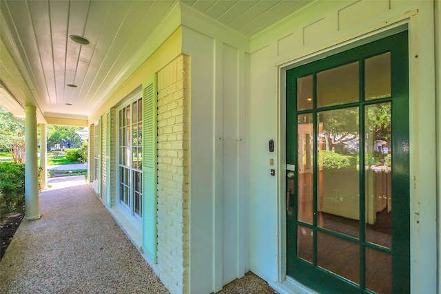 entrance to property with brick siding and a porch