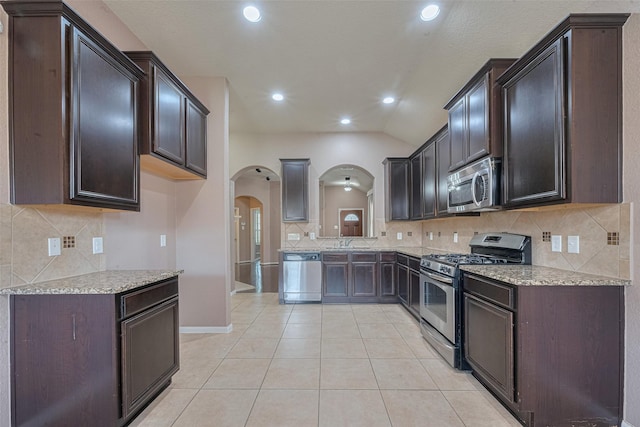 3603 Canvasback Ln, Houston, TX 77047 - kitchen with appliances with stainless steel finishes, arched walkways, a sink, tasteful backsplash, and light tile patterned floors
