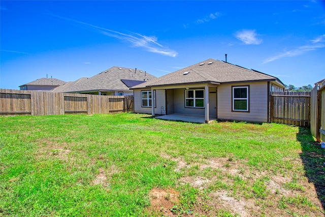 back of property with a yard, a patio, roof with shingles, and a fenced backyard