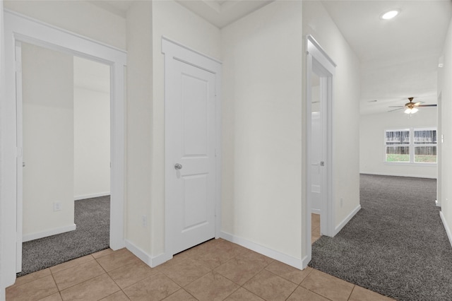 hallway featuring light colored carpet, light tile patterned floors, and baseboards