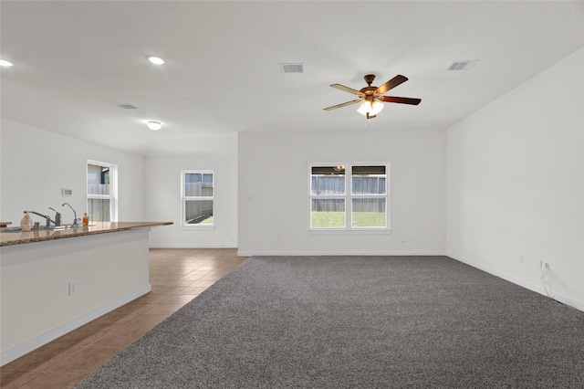 tiled spare room featuring baseboards, visible vents, ceiling fan, and a sink
