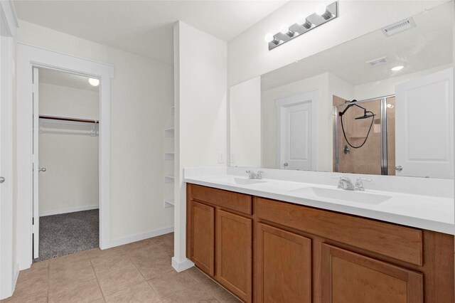 full bath featuring a sink, visible vents, tile patterned floors, a shower stall, and a walk in closet