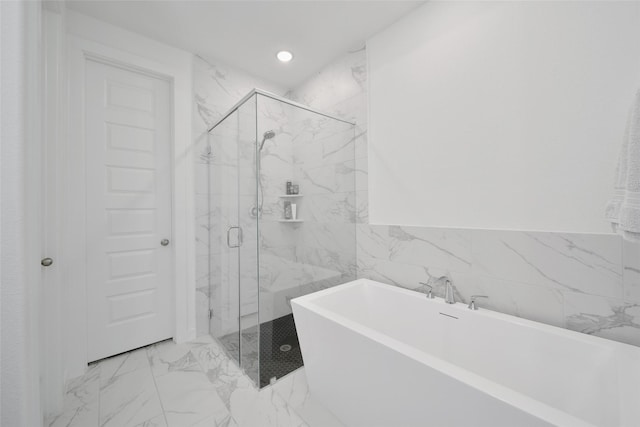 bathroom with a marble finish shower, marble finish floor, tile walls, and a freestanding tub