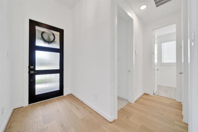 entryway with baseboards, light wood finished floors, and visible vents