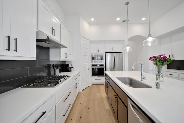 kitchen featuring a sink, stainless steel appliances, white cabinetry, under cabinet range hood, and light countertops