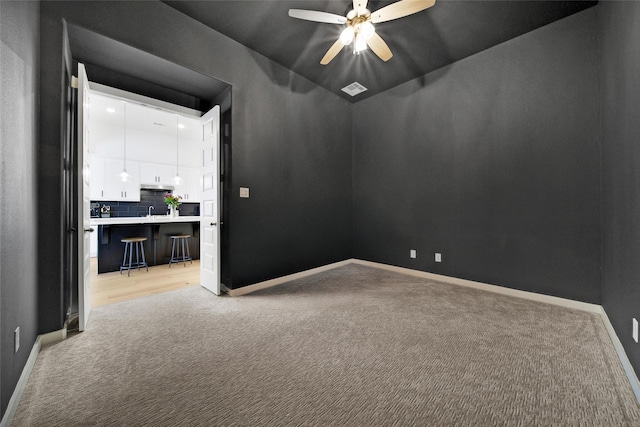 empty room featuring a ceiling fan, light carpet, and baseboards