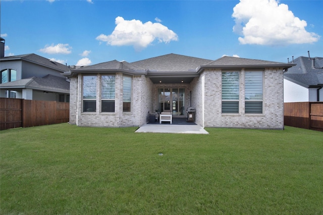 rear view of house featuring a yard, brick siding, a fenced backyard, and a patio
