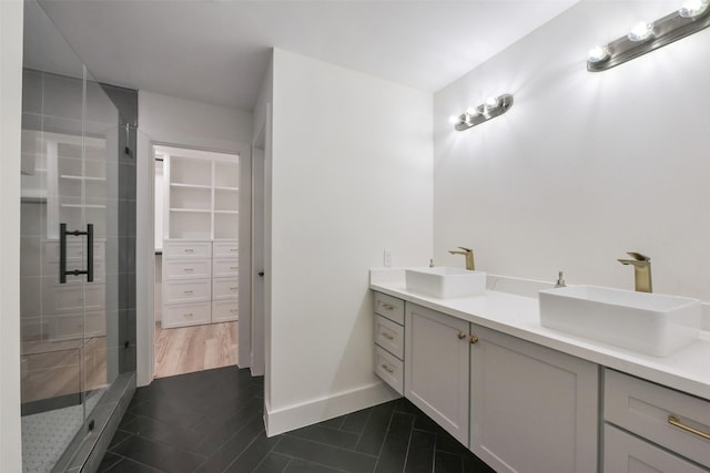 full bathroom featuring double vanity, a shower stall, and a sink