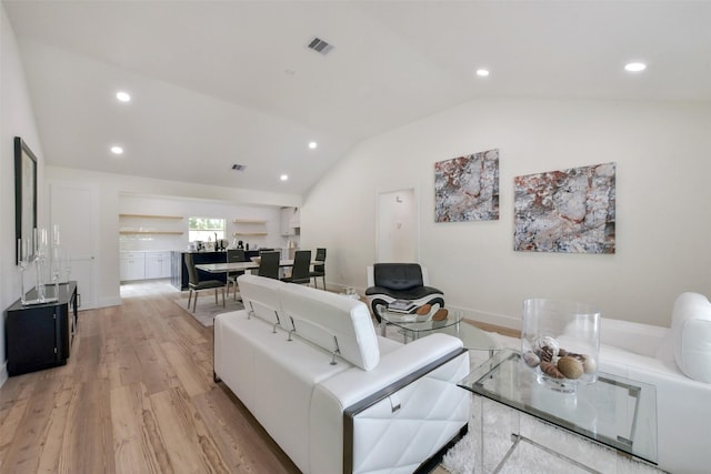 living room featuring lofted ceiling, light wood-style flooring, visible vents, and recessed lighting