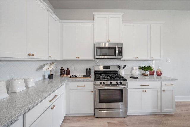 kitchen featuring white cabinets, appliances with stainless steel finishes, decorative backsplash, and light wood-style floors