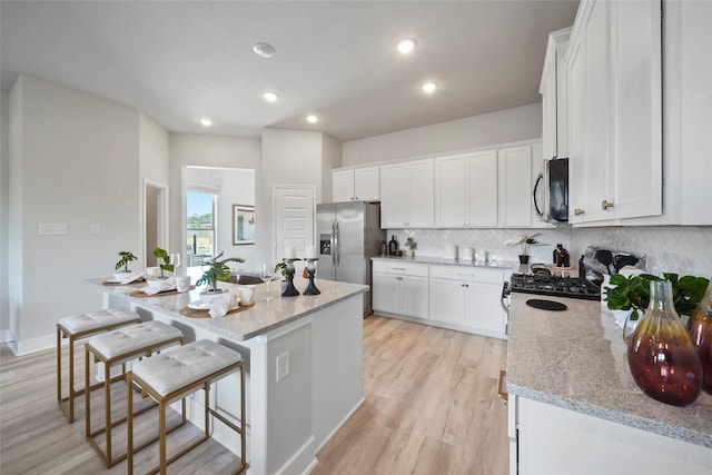 kitchen with a sink, stainless steel appliances, backsplash, and white cabinets