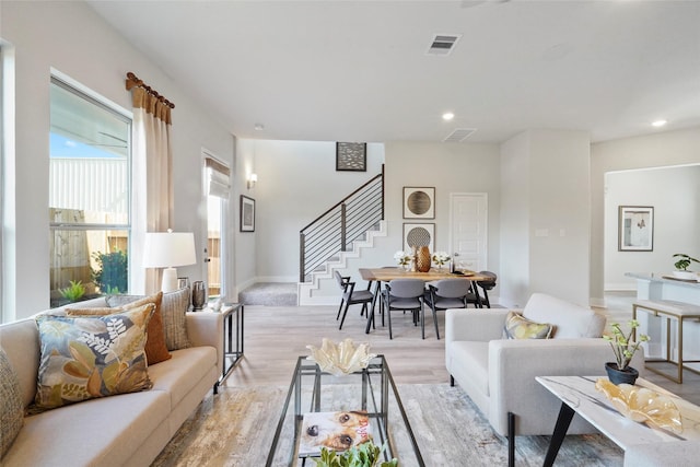 living area with stairway, light wood-style flooring, visible vents, and recessed lighting