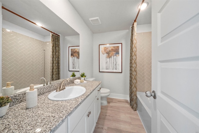 full bathroom with toilet, baseboards, visible vents, vanity, and wood finished floors