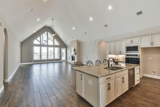 11131 Heartleaf Aster Way, Cypress, TX 77433 - kitchen featuring visible vents, a sink, open floor plan, arched walkways, and appliances with stainless steel finishes