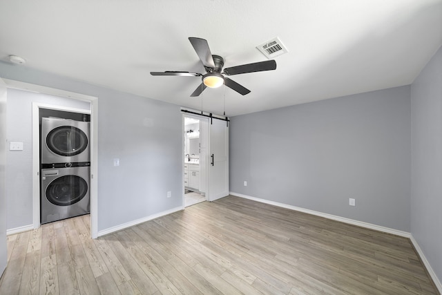 315 Lakeview Hbr, Onalaska, TX 77360 - washroom featuring stacked washer / drying machine, a barn door, ceiling fan, and light wood-style floors