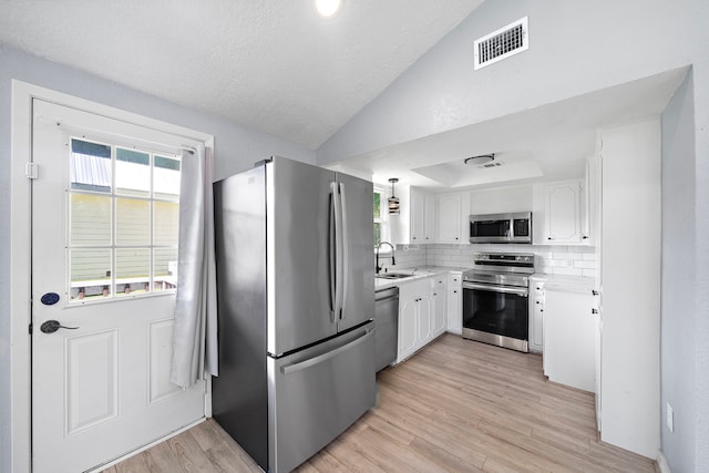 315 Lakeview Hbr, Onalaska, TX 77360 - kitchen featuring stainless steel appliances, a sink, white cabinetry, vaulted ceiling, and light wood-style flooring