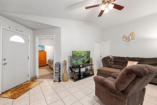 living room with a ceiling fan, light tile patterned floors, lofted ceiling, and a textured ceiling