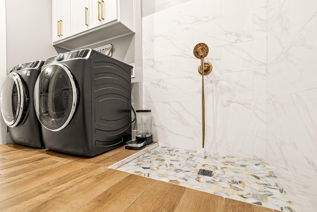 8577 Majestic Lake Ct, Montgomery, TX 77316 - clothes washing area featuring washing machine and dryer, light wood-style flooring, and cabinet space
