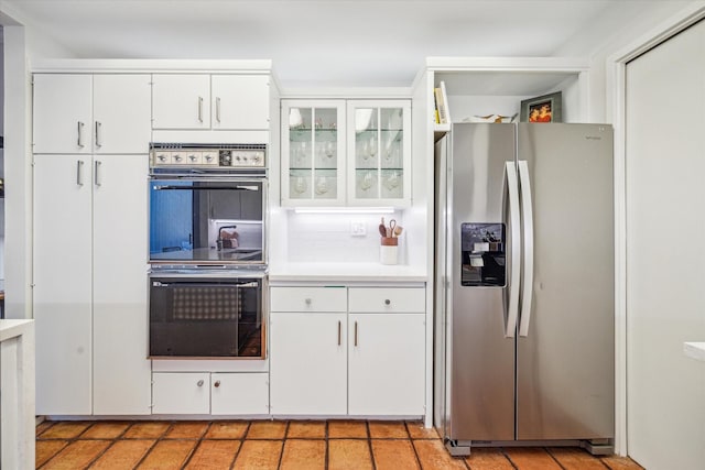 167 Litchfield Ln, Houston, TX 77024 - kitchen with stainless steel fridge with ice dispenser, double oven, light countertops, and white cabinets