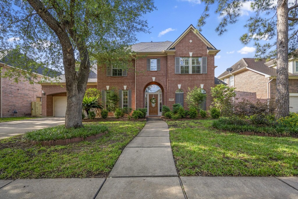 22911 Jamie Brook Ln, Katy, TX 77494 - colonial-style house with brick siding, concrete driveway, a front lawn, and a garage