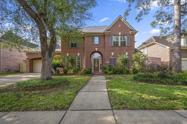 colonial-style house with brick siding, concrete driveway, a front lawn, and a garage