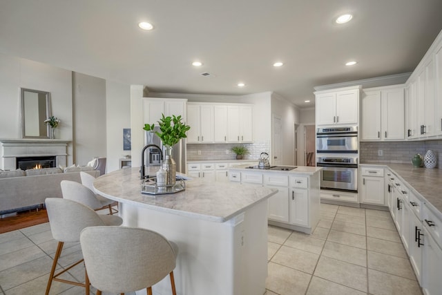 kitchen featuring a center island with sink, light tile patterned floors, backsplash, and recessed lighting