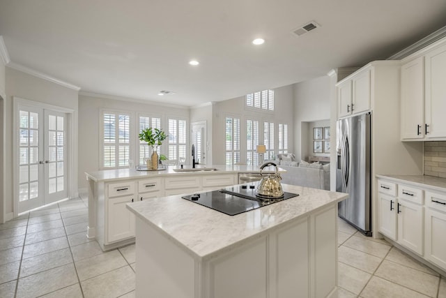 kitchen with a kitchen island, stainless steel fridge, black electric cooktop, a sink, and ornamental molding
