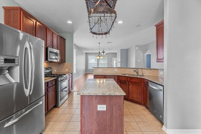 kitchen featuring a center island, a sink, a peninsula, decorative backsplash, and appliances with stainless steel finishes