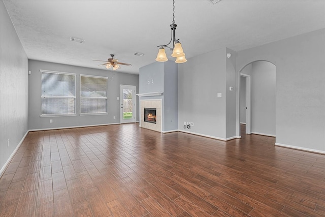 unfurnished living room featuring ceiling fan, baseboards, dark wood-type flooring, and arched walkways