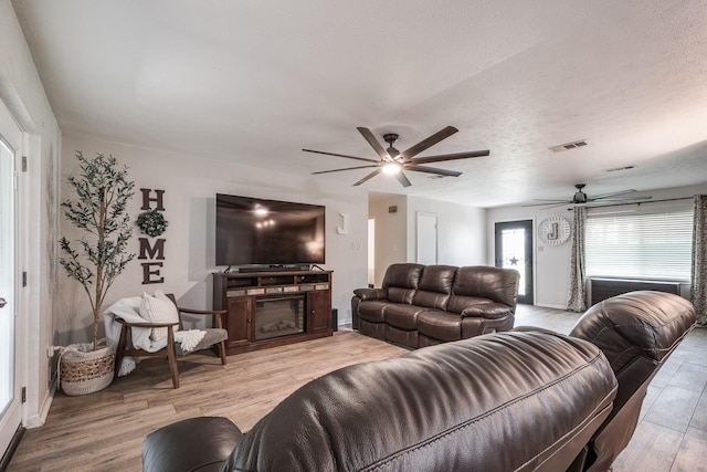 living area with baseboards, visible vents, light wood-style flooring, and a ceiling fan