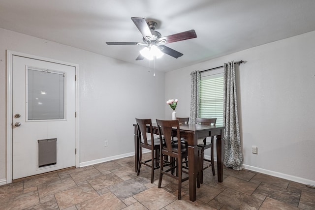 dining area featuring baseboards, a ceiling fan, and stone finish flooring