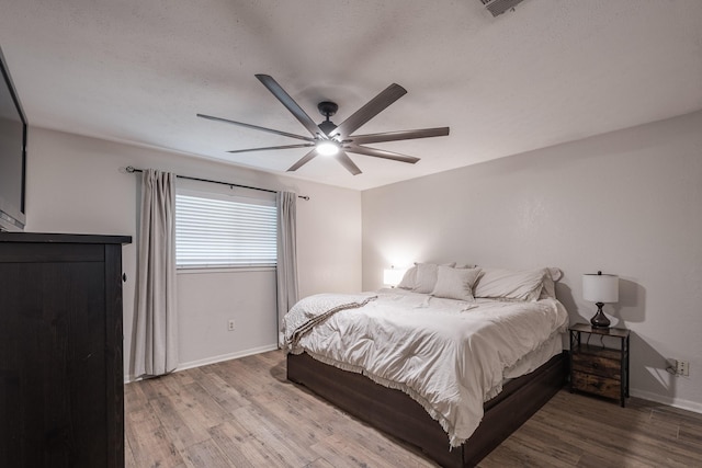 bedroom with baseboards, ceiling fan, and wood finished floors