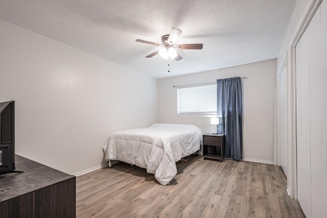 bedroom with a closet, a ceiling fan, wood finished floors, and baseboards