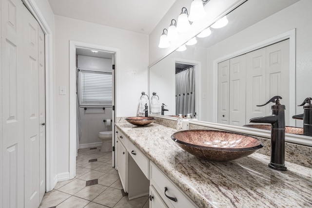 full bathroom with vanity, toilet, a closet, and tile patterned floors