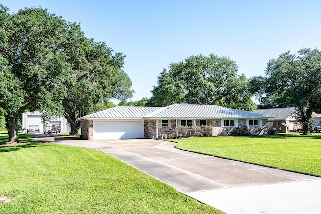 ranch-style home featuring an attached garage, metal roof, a front yard, driveway, and a standing seam roof