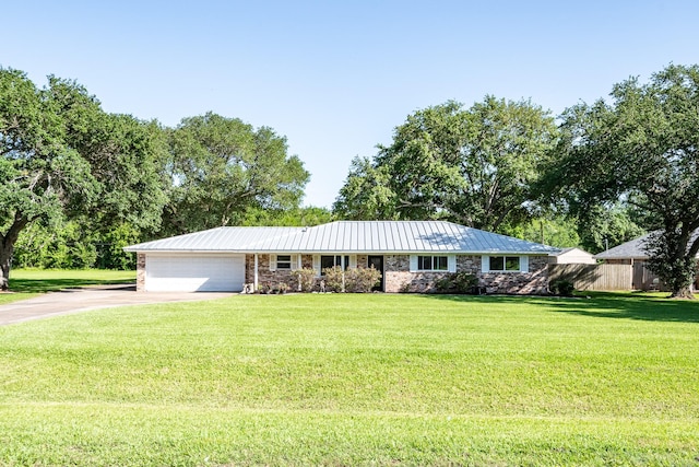 ranch-style house featuring a front lawn, driveway, a garage, and metal roof