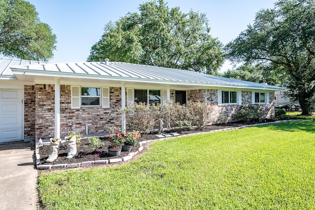 single story home with a porch, brick siding, a front yard, metal roof, and a standing seam roof