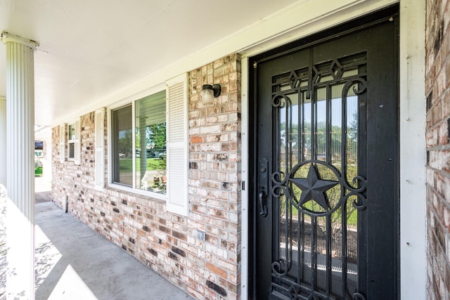 entrance to property with covered porch and brick siding