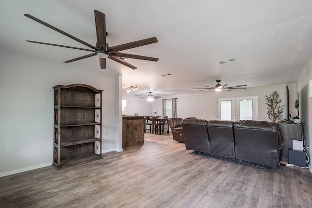living area featuring visible vents, wood finished floors, baseboards, and ceiling fan
