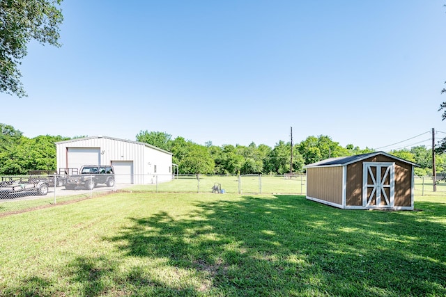 view of yard featuring fence, a detached garage, and an outbuilding