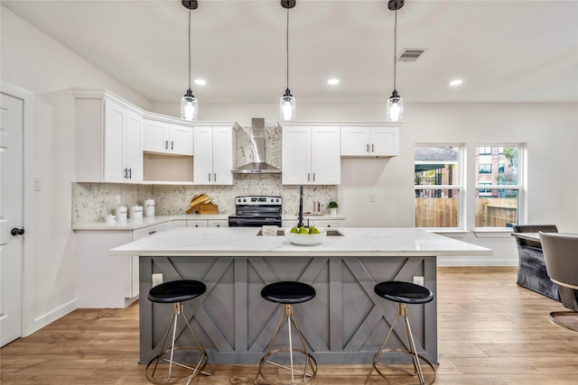 4104 Engelke St, Houston, TX 77003 - kitchen featuring white cabinetry, decorative backsplash, stainless steel electric range, and wall chimney exhaust hood