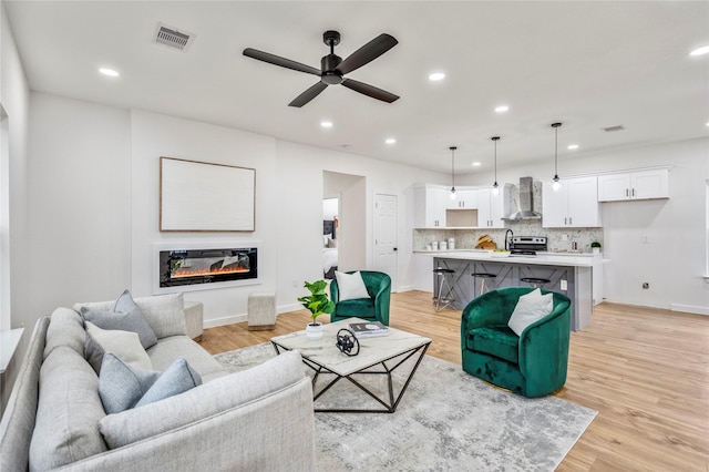 4104 Engelke St, Houston, TX 77003 - living room featuring visible vents, recessed lighting, light wood finished floors, a ceiling fan, and a glass covered fireplace