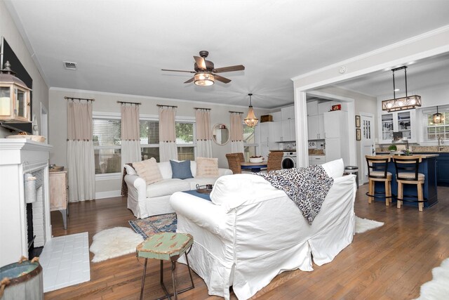 419 E Bell Ave, Crockett, TX 75835 - living room featuring hardwood / wood-style flooring, washer / dryer, ornamental molding, visible vents, and a ceiling fan