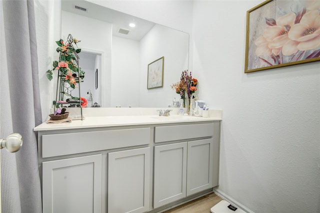 bathroom with a sink, double vanity, baseboards, and visible vents