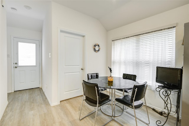 dining space featuring lofted ceiling, baseboards, and light wood-type flooring